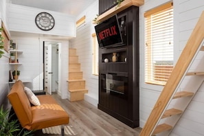 Un intérieur moderne avec un escalier, un canapé, une cheminée et une horloge au mur.