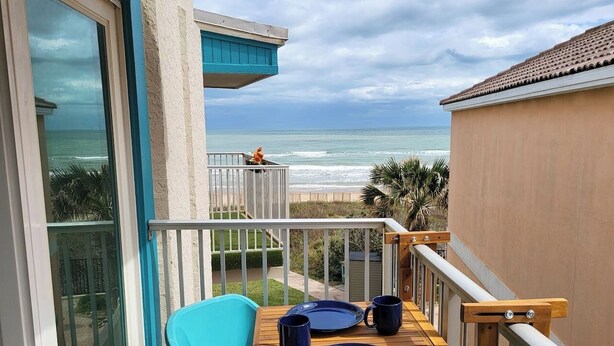 Een balkon met een tafel, stoelen en uitzicht op de oceaan.