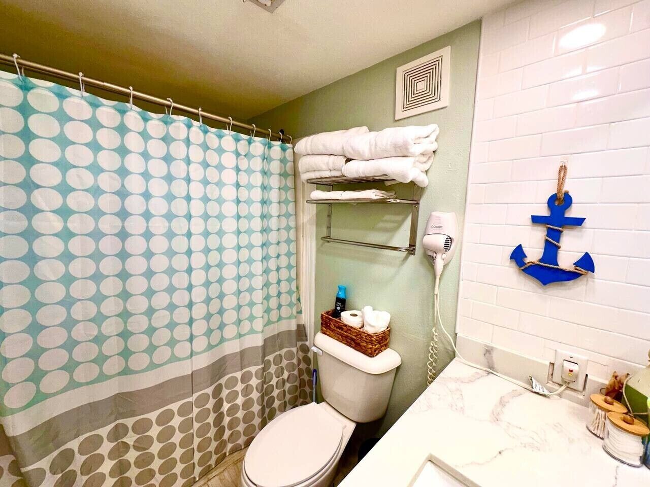 Een badkamer met toilet, douchegordijn, handdoekhouder en een wandhanddoekhouder.