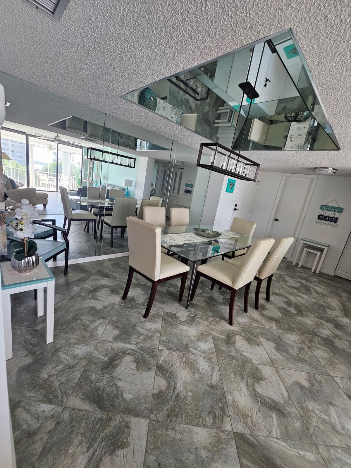 Un espace repas moderne avec une table et des chaises en verre, un plafond haut doté d’une verrière et une vue sur l’extérieur.
