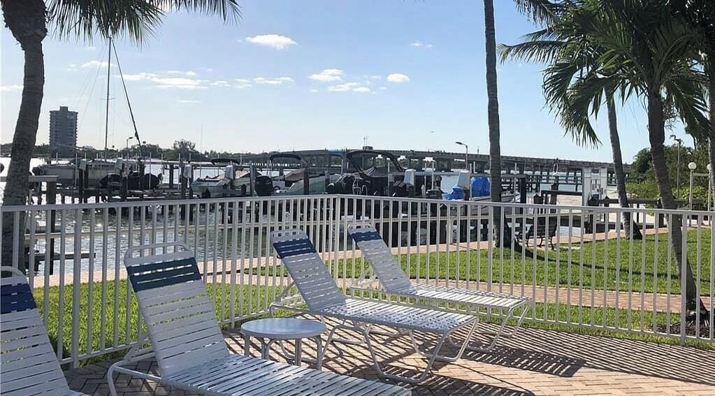 A waterfront patio with lounge chairs and a view of the marina.