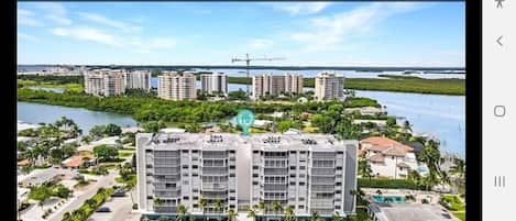 A high-rise hotel with multiple floors, surrounded by greenery and a body of water.