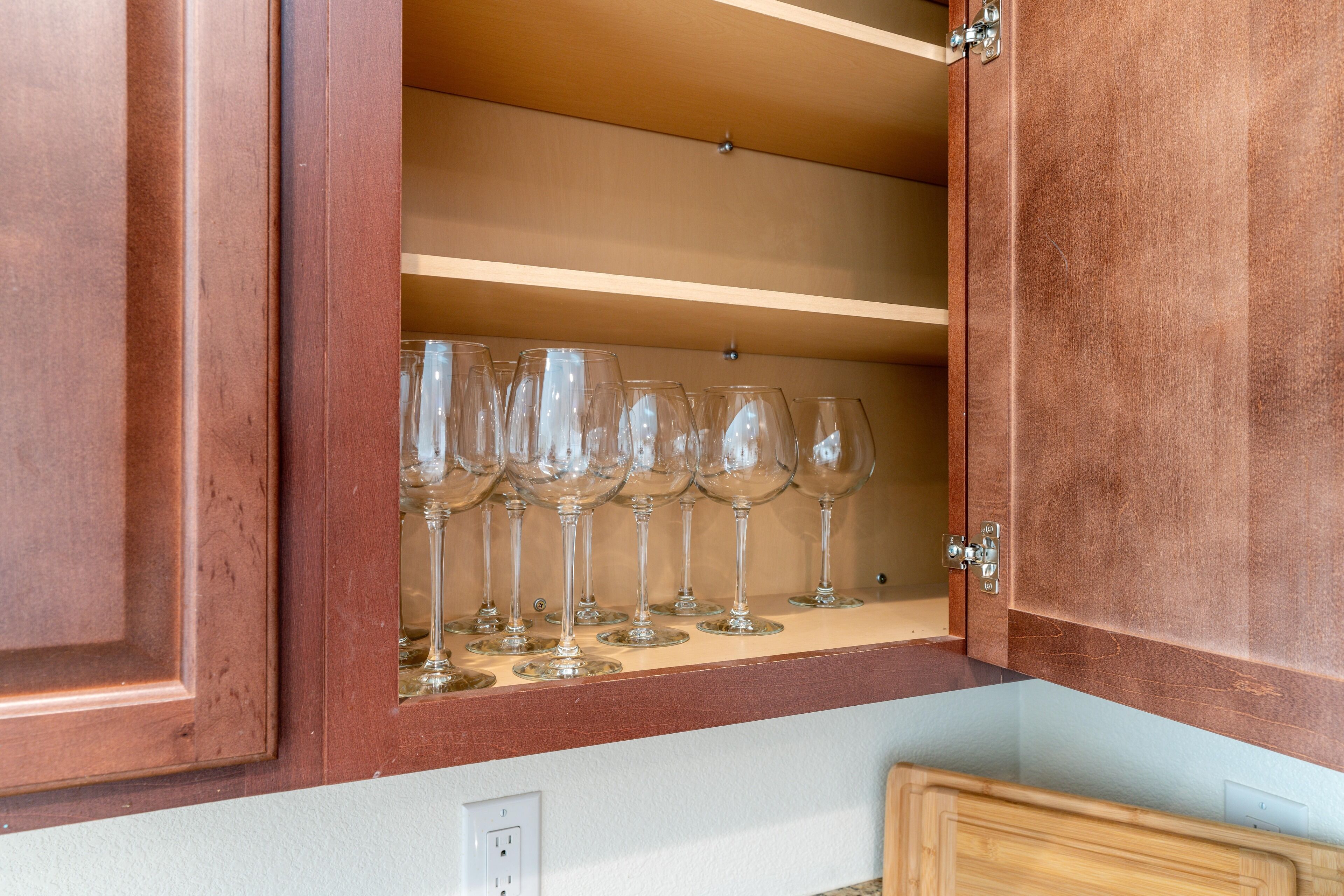 A wooden cabinet with a shelf holding multiple wine glasses.