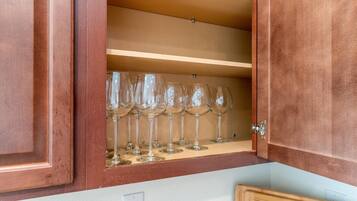 A wooden cabinet with a shelf holding multiple wine glasses.
