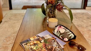 Une table en bois, avec un menu, une bougie et un vase rempli de fleurs.
