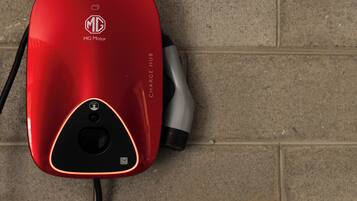 A red MG Motor electric vehicle charging station with a cable connected to it.