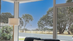 Una habitación con un amplio ventanal que ofrece vistas a una carretera y árboles.