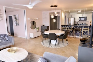 Uma sala de estar moderna com área de jantar, cozinha e um ventilador de teto.
