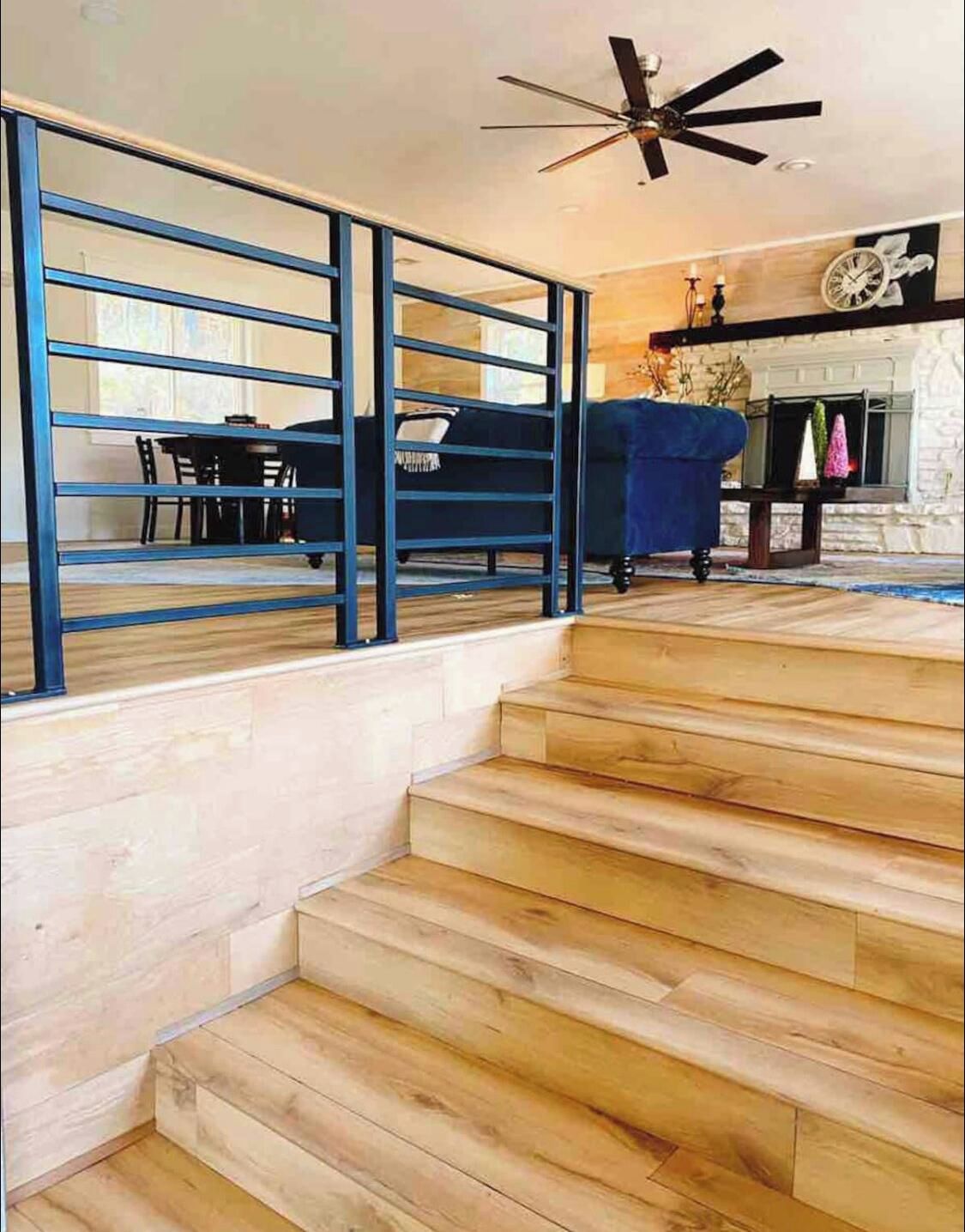 A staircase with wooden steps leading to a living area with a blue sofa and a fireplace.
