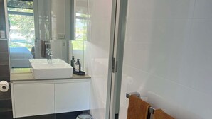 Ein modernes Badezimmer mit einem großen Spiegel, weißen Fliesen, einem Waschbecken und einem Handtuchhalter.