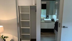 Ein Schlafzimmer mit Bett, Nachttisch mit Lampe und Schrank mit Regalen.