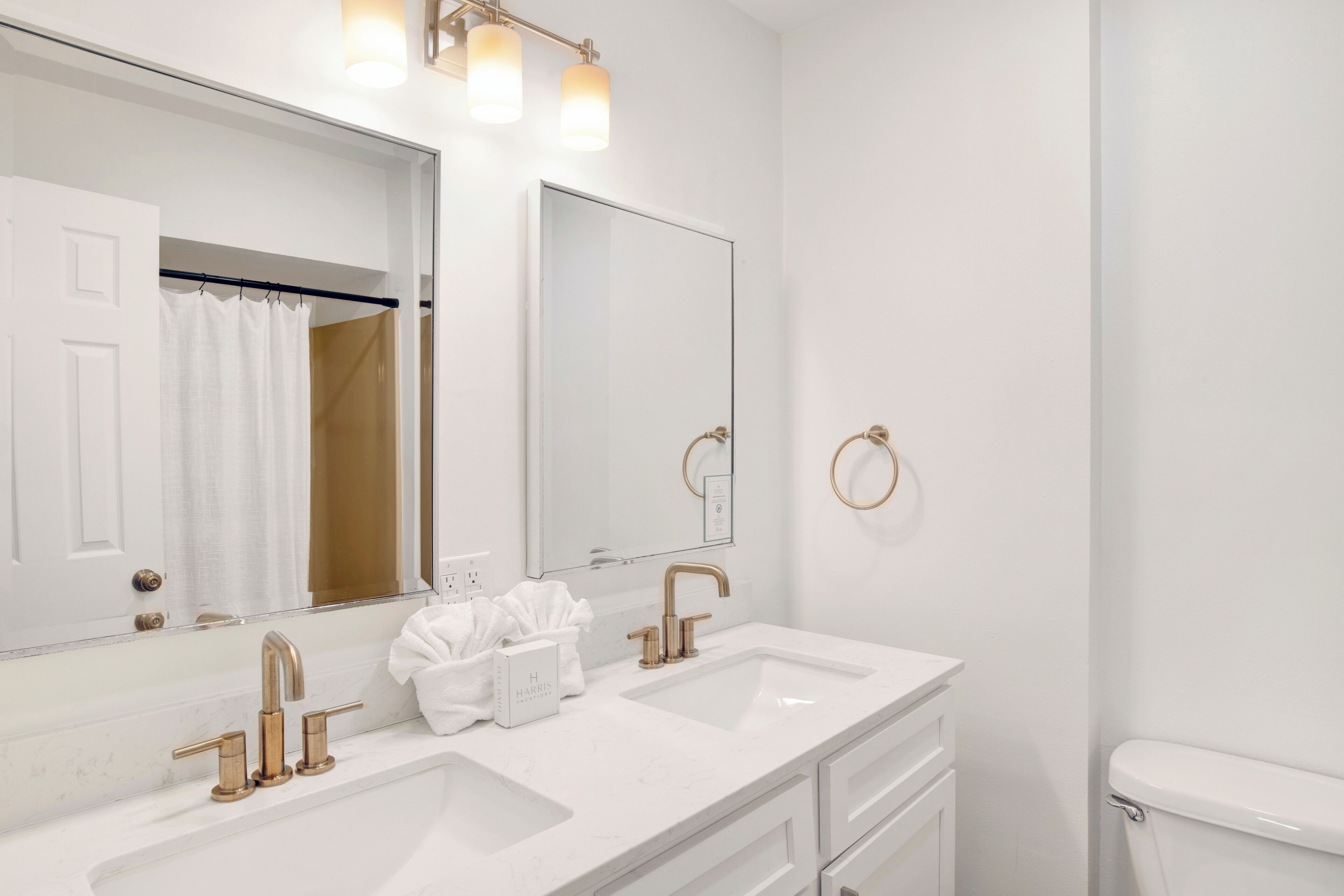 A modern bathroom with two sinks, a large mirror, and a toilet.