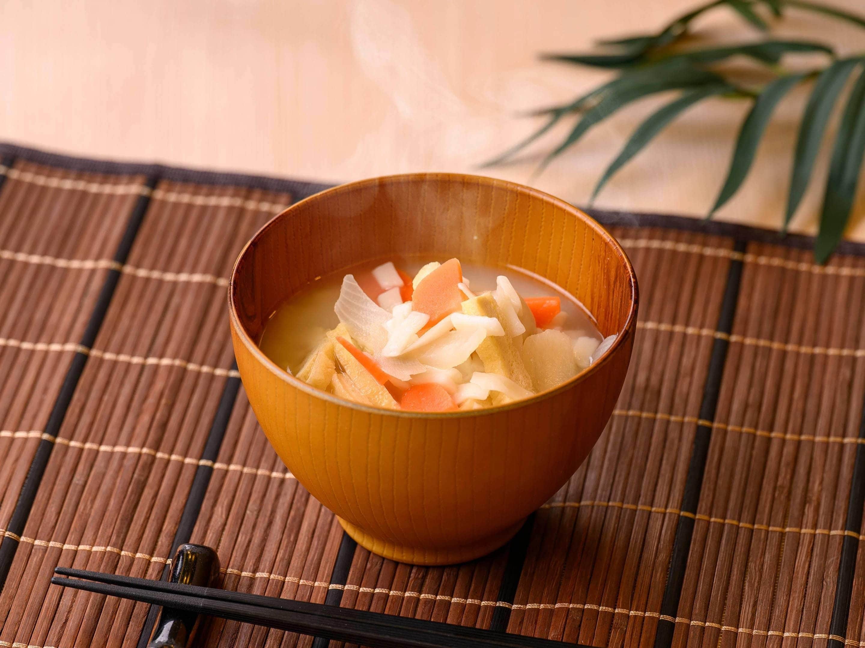 A bowl of soup on a bamboo mat.