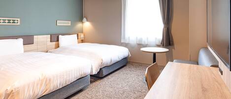 A hotel room with two beds, a small round table, a TV, and a window with curtains.