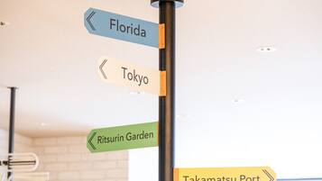 A directional signpost with arrows pointing to Florida, Tokyo, Ritsurin Garden, and Takamatsu Port.