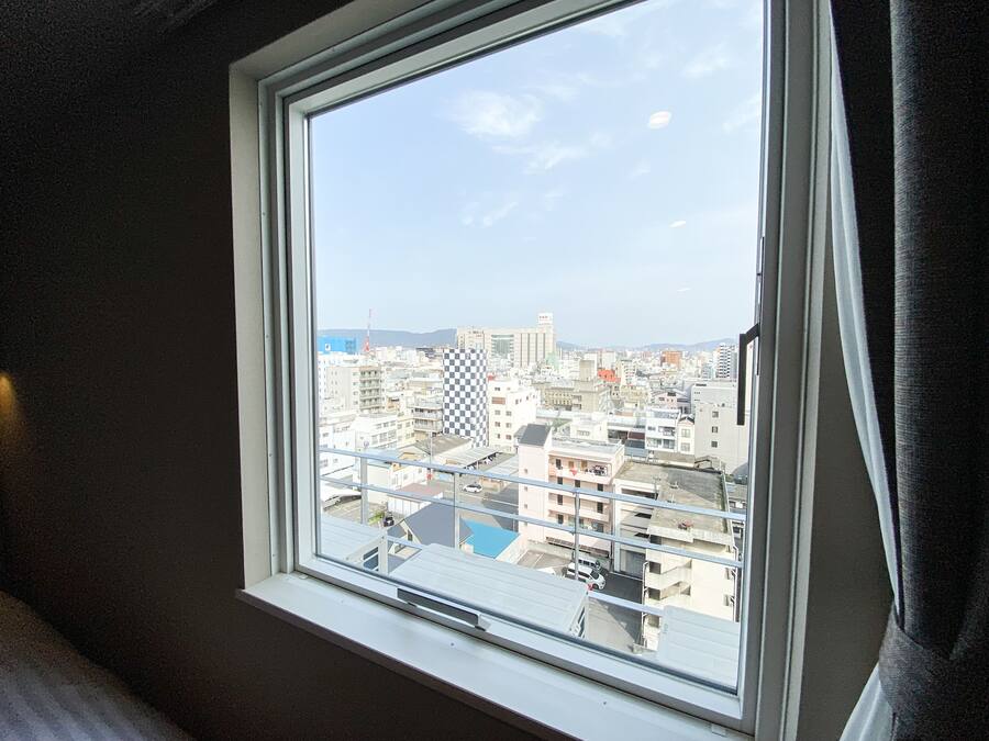 Una ventana con vista a un paisaje urbano, incluyendo edificios y cielo despejado.