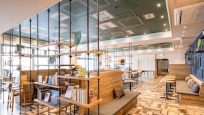 A modern library with wooden bookshelves, a central seating area, and a patterned wooden floor. - Comfort Hotel Takamatsu (Takamatsu)