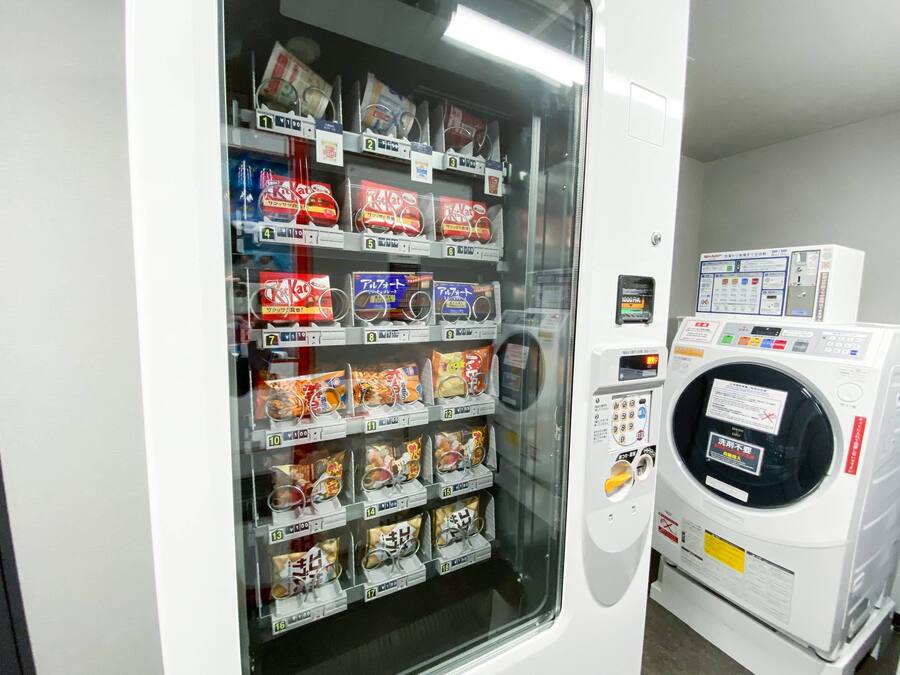 A vending machine with various snack packages, a control panel, and a washing machine.
