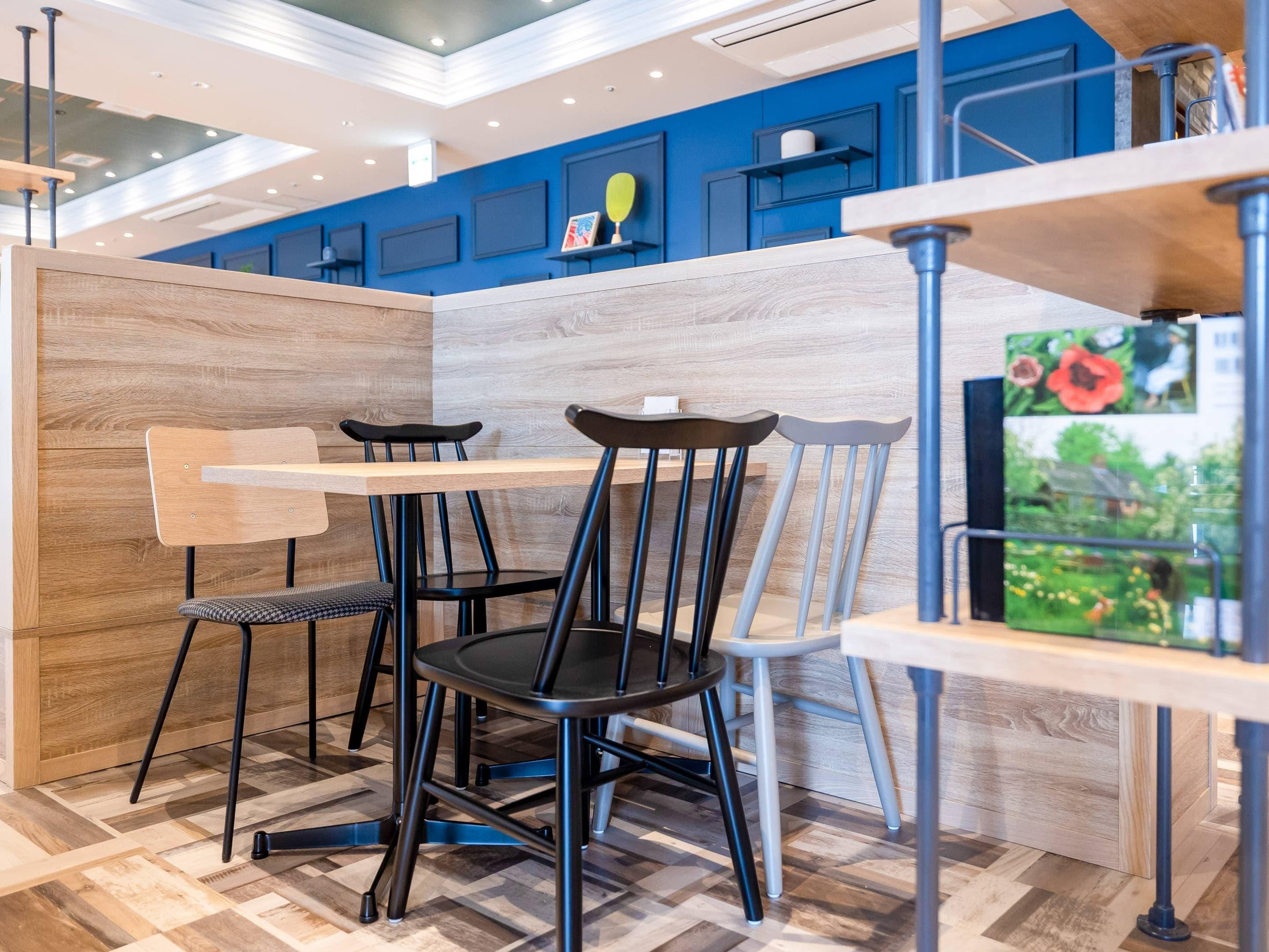 A modern dining area with a wooden partition, black and grey chairs, and a blue accent wall.