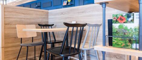 A modern dining area with a wooden partition, black and grey chairs, and a blue accent wall.