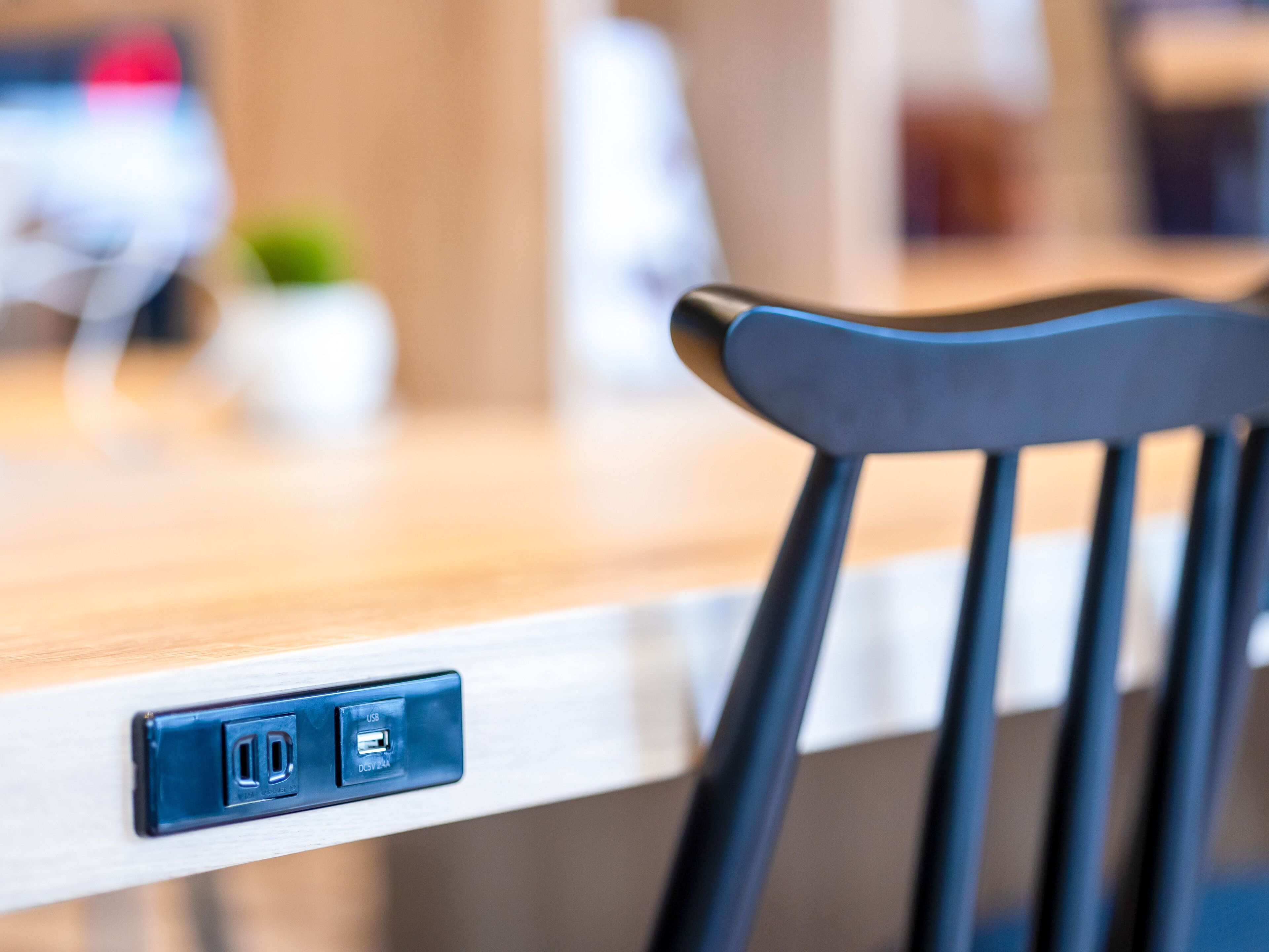 Una silla moderna con un puerto USB y un enchufe en una mesa de madera.
