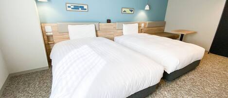 Une chambre d’hôtel avec un lit double, deux tables de chevet, une tête de lit et un mur d’accent bleu.
