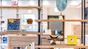 A multi-tiered wooden shelf with various items including books, a glass vase, and a decorative bowl.