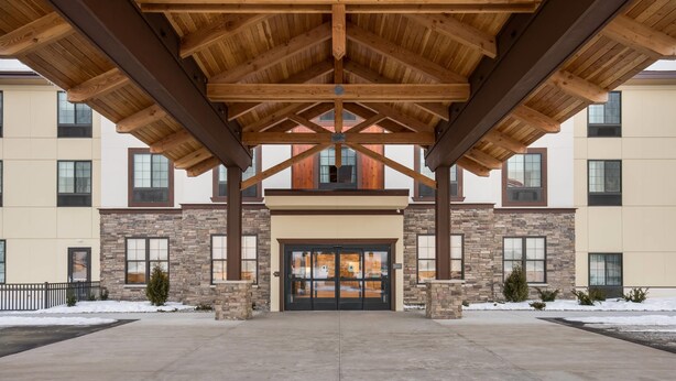 A building with a stone facade, large windows, and a wooden roof structure. - MainStay Suites Gaylord (Gaylord)