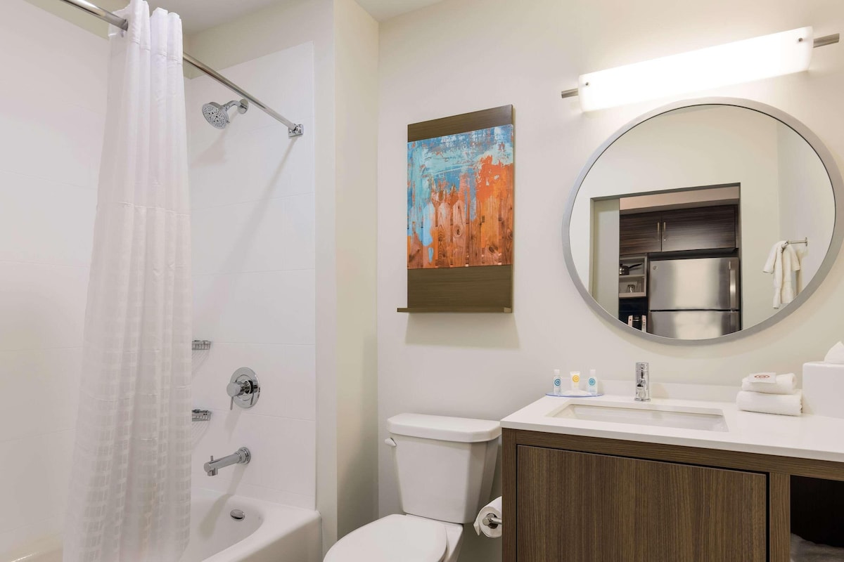 Un baño con ducha, inodoro, lavabo y un espejo grande.