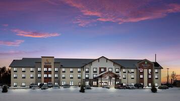 A hotel with a large parking lot and a snow-covered ground.