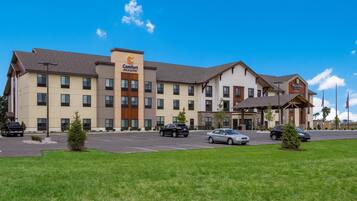 Un hôtel à plusieurs étages, avec une enseigne « Comfort Inn & Suites », une autre enseigne « Main Stay Suites » et un parking où sont garées plusieurs voitures.