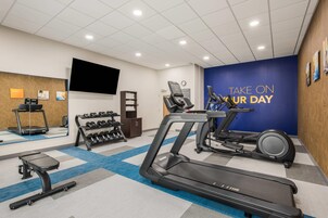 A gym with treadmills, dumbbells, and a wall with motivational text.