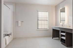 A modern bathroom with a large window, a dark wood vanity, and a white tiled floor.