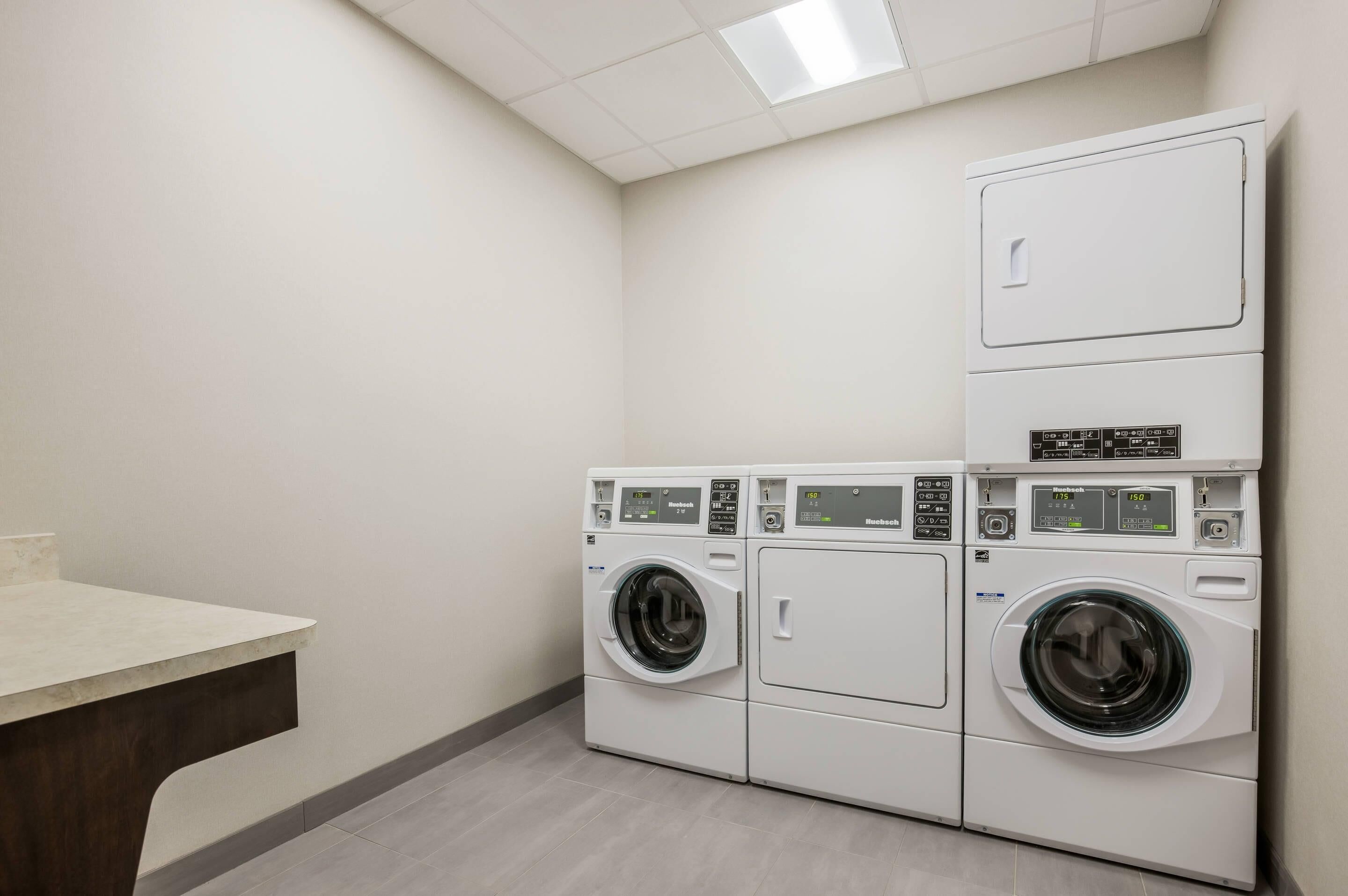A laundry room with two front-loading washing machines and a table.