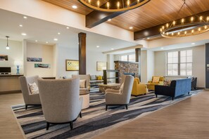 A spacious living area with modern furniture, a stone fireplace, and a large window providing natural light. - Comfort Inn & Suites Gaylord (Gaylord)