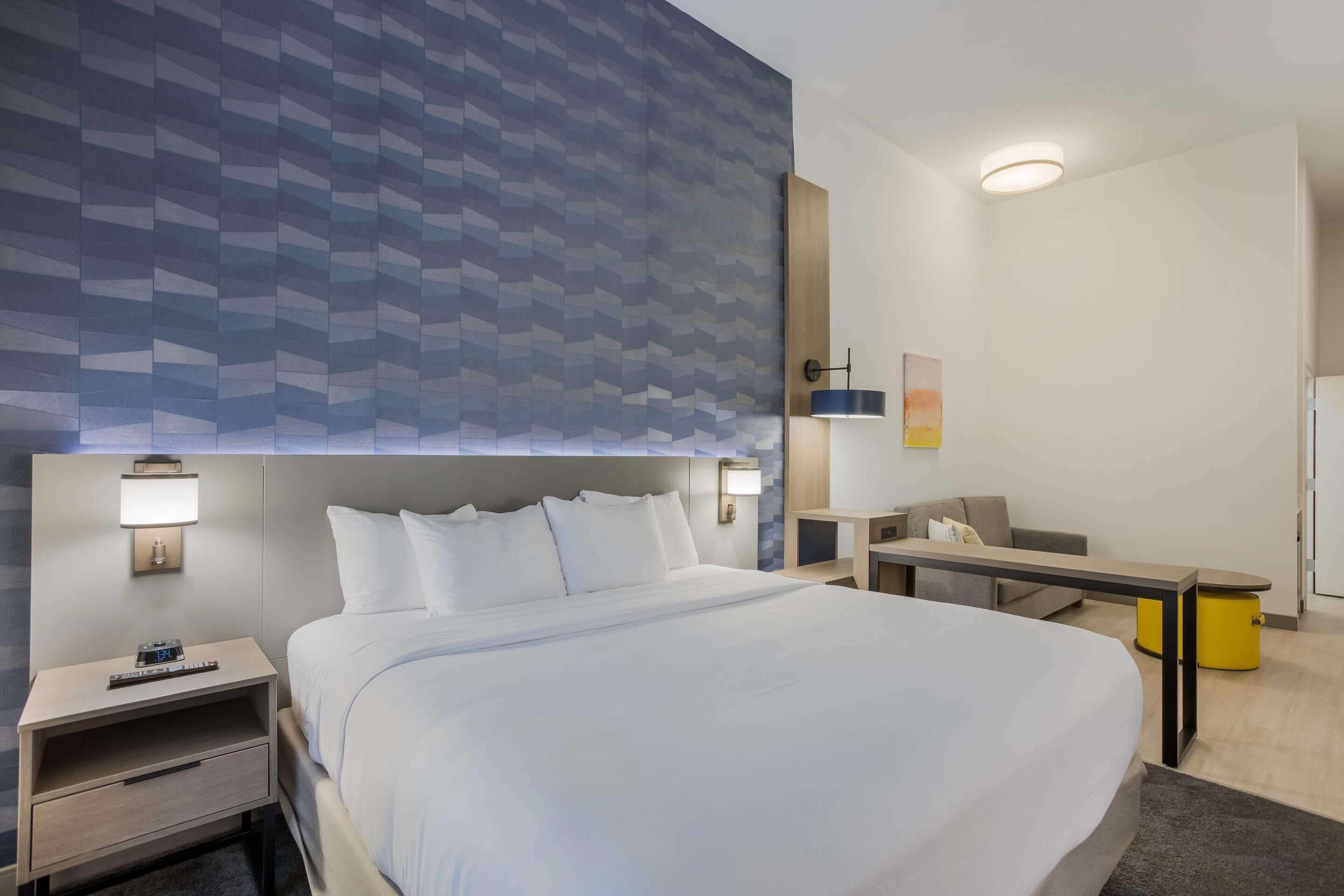 A hotel room with a large bed, bedside tables, a desk, and a chair.