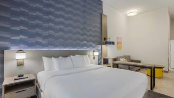 A hotel room with a large bed, bedside tables, a desk, and a chair.