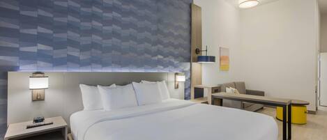 Una habitación de hotel con una cama grande, mesitas de noche, un escritorio y una silla.