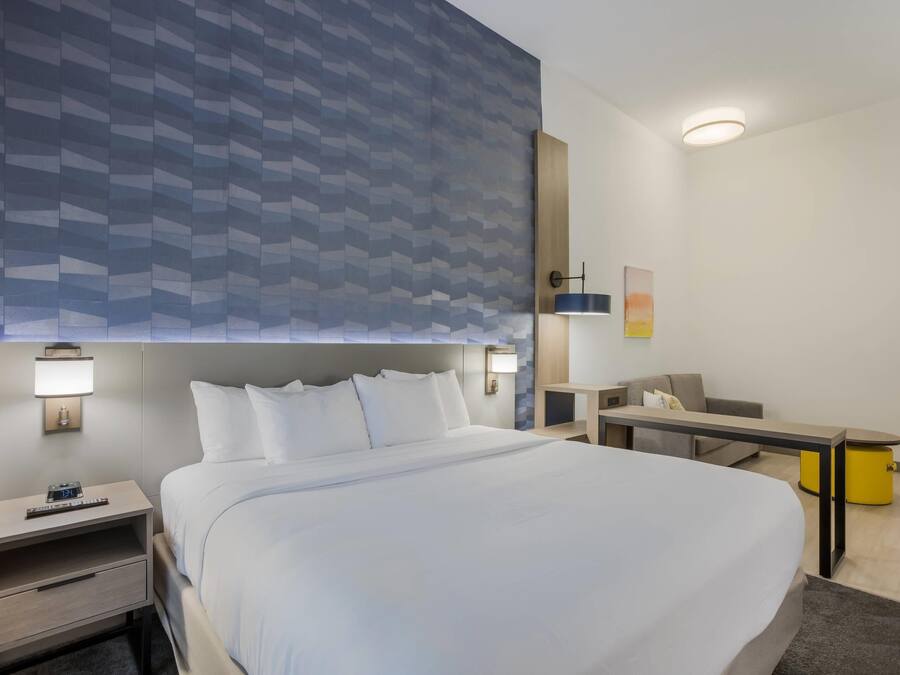 A hotel room with a large bed, bedside tables, a desk, and a chair.