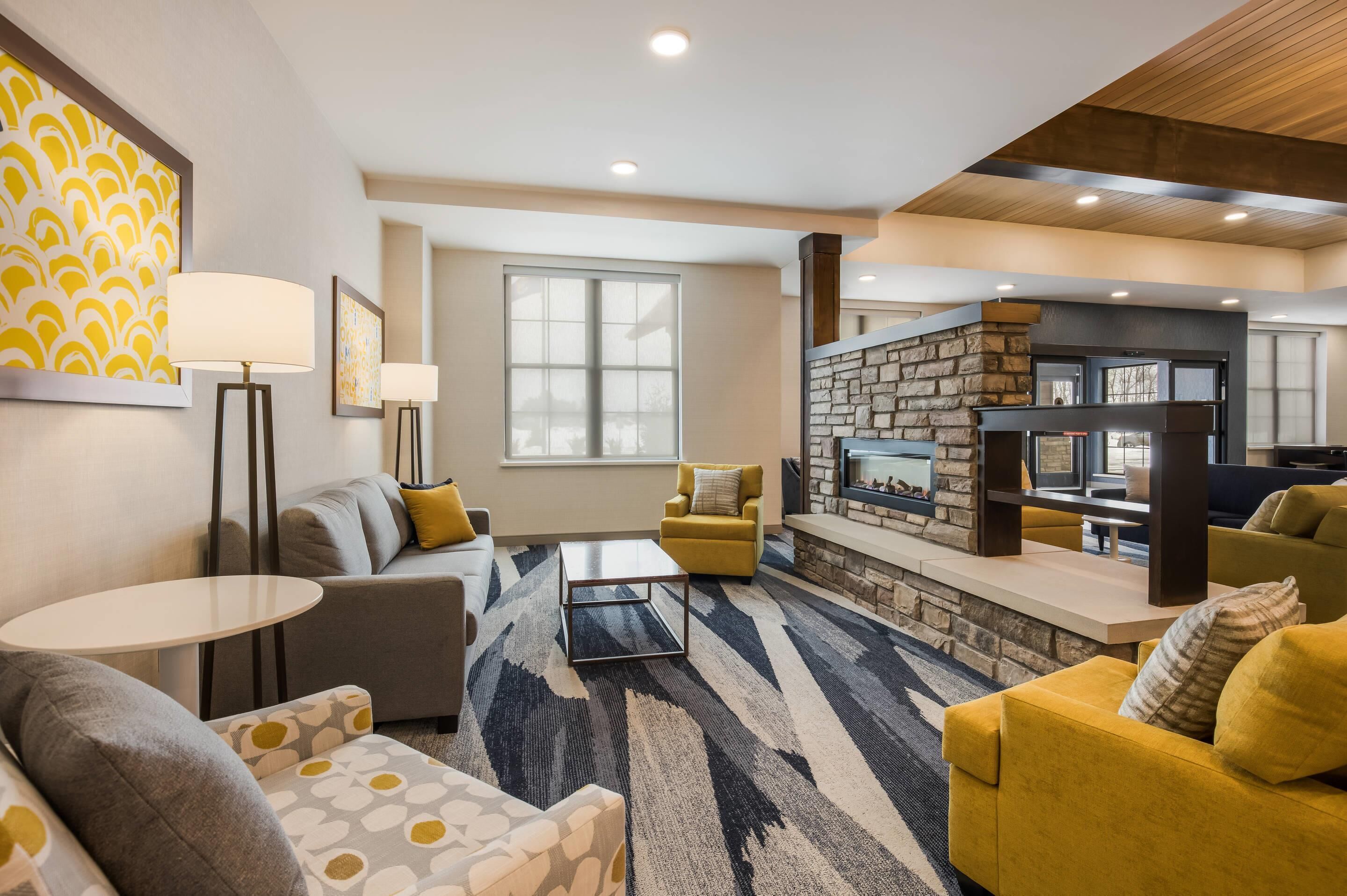 A modern living room with a sofa, armchairs, a coffee table, and a fireplace.