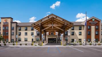 A hotel with a covered entrance, multiple floors, and a parking lot with handicapped parking spaces.