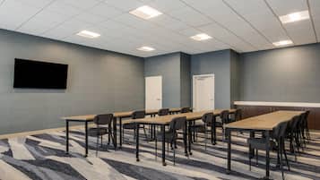 Une salle de conférence équipée d’une grande table, de chaises, d’un téléviseur à écran plat et d’un sol recouvert de moquette.