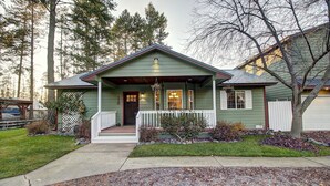 Ein grünes Haus mit Veranda, Eingangstür und einem kleinen Garten.