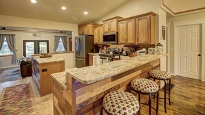 Eine Küche mit Holzschränken, einer Granit-Arbeitsplatte, einem Kühlschrank, einer Mikrowelle und Barhocker.