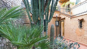 A courtyard with cacti and a stone wall, a door, and a balcony with a railing. - Waterfront apartment with beach access (Santa Flavia)