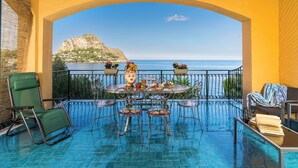 A sunlit outdoor seating area with a view of the sea and a mountain. - Waterfront apartment with beach access (Santa Flavia)