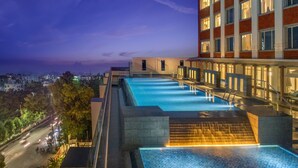 Una piscina infinita en la azotea con vistas a la ciudad al atardecer.