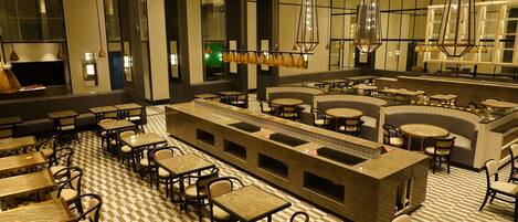 A modern restaurant with a checkered floor, multiple seating areas, and hanging pendant lights.