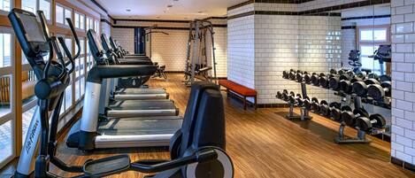 A gym with treadmills, elliptical machines, and weight benches.