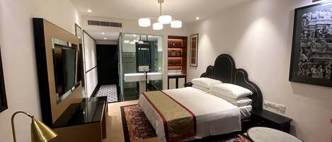 A hotel room with a bed, bedside table, desk, chair, and a small round table.